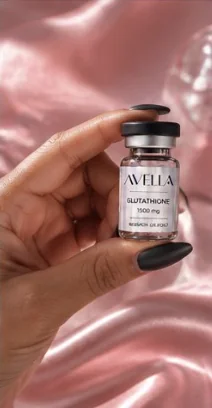 Hand holding an AVELLA Glutathione 1500 mg vial against pink satin